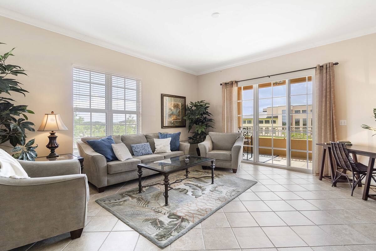 A living room with a sofa set, a coffee table, a lamp, and a view of a balcony.
