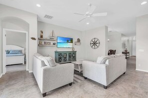 Ein modernes Wohnzimmer mit zwei Sofas, einem Fernseher und einem Deckenventilator.