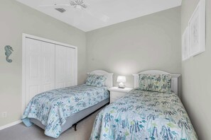 A bedroom with two beds, a ceiling fan, and a white door. - Pool Home in Spanish Wells with Public Golf (Bonita Springs)