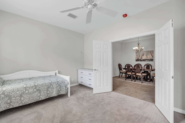 A bedroom with a bed, dresser, and a dining area with chairs and a table.