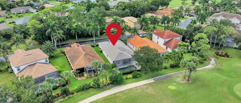 Zona residencial con casas, un campo de golf y un marcador rojo que indica una ubicación.