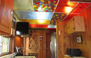 Une cuisine de taille réduite avec des murs en bois, un évier en acier inoxydable, un réfrigérateur et un four à micro-ondes.