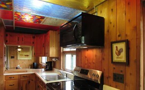Kitchen with a window offering a view of the outdoors, featuring a stove, sink, and microwave.
