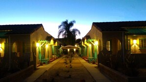 Un pasillo con varias habitaciones, cada una con puerta y ventana, que conduce a un espacio central abierto.
