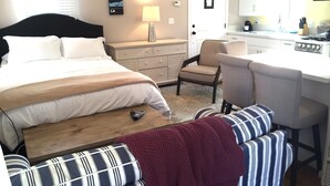 Una habitación de hotel con cama, escritorio, silla, mesita de noche y lámpara.