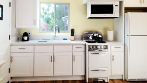 Una cocina con armarios blancos, estufa, microondas y refrigerador.