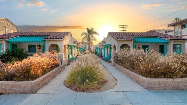 Filas de casas con un sendero central que conduce hacia el atardecer.