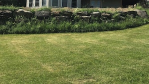 A two-story house with a large balcony and a stone retaining wall. - Relaxation in the mountains. Hike, Ski & explore around Jay Peak (Lowell)