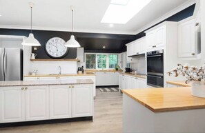 Kitchen features a central island, pendant lights, and a window with a clock above the sink.