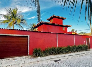 Um edifício vermelho com porta de garagem, uma pequena janela e uma porta.