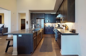 A modern kitchen with dark cabinetry, stainless steel appliances, and a central island.
