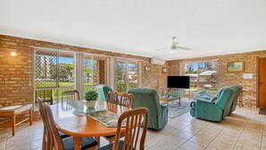 A spacious living area with a dining table, chairs, a sofa, and a TV.