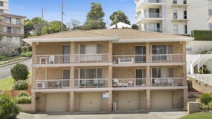 A two-story building with a brick facade, multiple balconies, and a garage entrance.