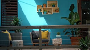 A balcony with wicker furniture, a wooden railing, and potted plants. - Cocoloba #2 at Crash Boat - A Unique Beach Front Experience (Aguadilla)