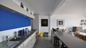 Eine moderne Küche mit blauer Akzentwand, einer Spüle, einem Wasserkocher und einer Bar mit Hockern.