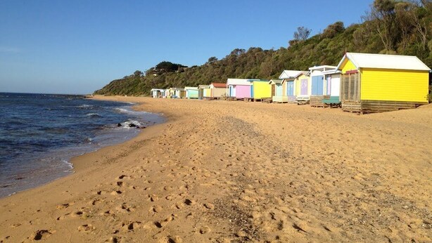 A beach with colorful beach huts aligned along the shore. -  Eliza Stays" Getaway. (Mount Eliza)