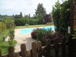 Une piscine entourée d’une végétation luxuriante et délimitée par une clôture en bois.