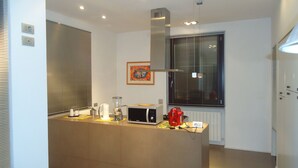 Una cucina moderna con isola centrale, elettrodomestici integrati e un'ampia finestra con persiane.
