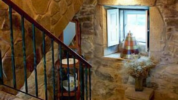A stone interior with a staircase, a window with a view, and a decorative item on the windowsill.