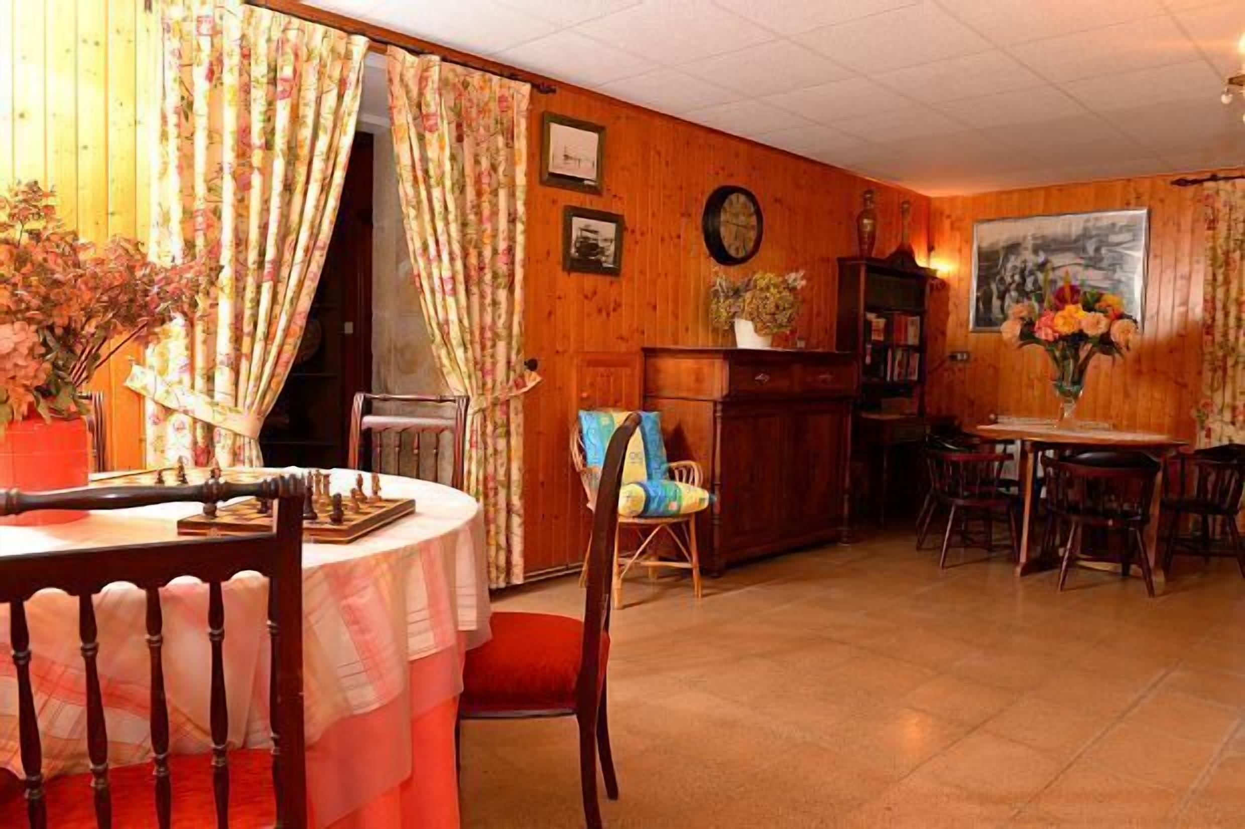 Un comedor con mesa de madera, sillas y un cortinaje floral.
