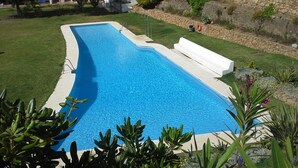 Piscina con parete in pietra e zona verde.