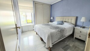 Una camera da letto con un letto, comodini, una ventola a soffitto e una finestra con persiane.