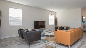 Un salon moderne avec un canapé, des fauteuils, une table basse et un téléviseur.