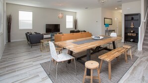 Un salon spacieux avec une table à manger en bois, des sièges confortables et un téléviseur.