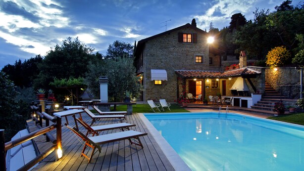 A swimming pool with lounge chairs, a stone house with a tiled roof, and a wooden deck. - Villa immersed in the nature, relax and privacy, private pool and garden (Castiglion Fiorentino)