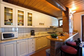 Enjoy a well-equipped kitchen with glass-fronted cabinets, microwave, and coffee maker, perfect for casual dining at the stone island.