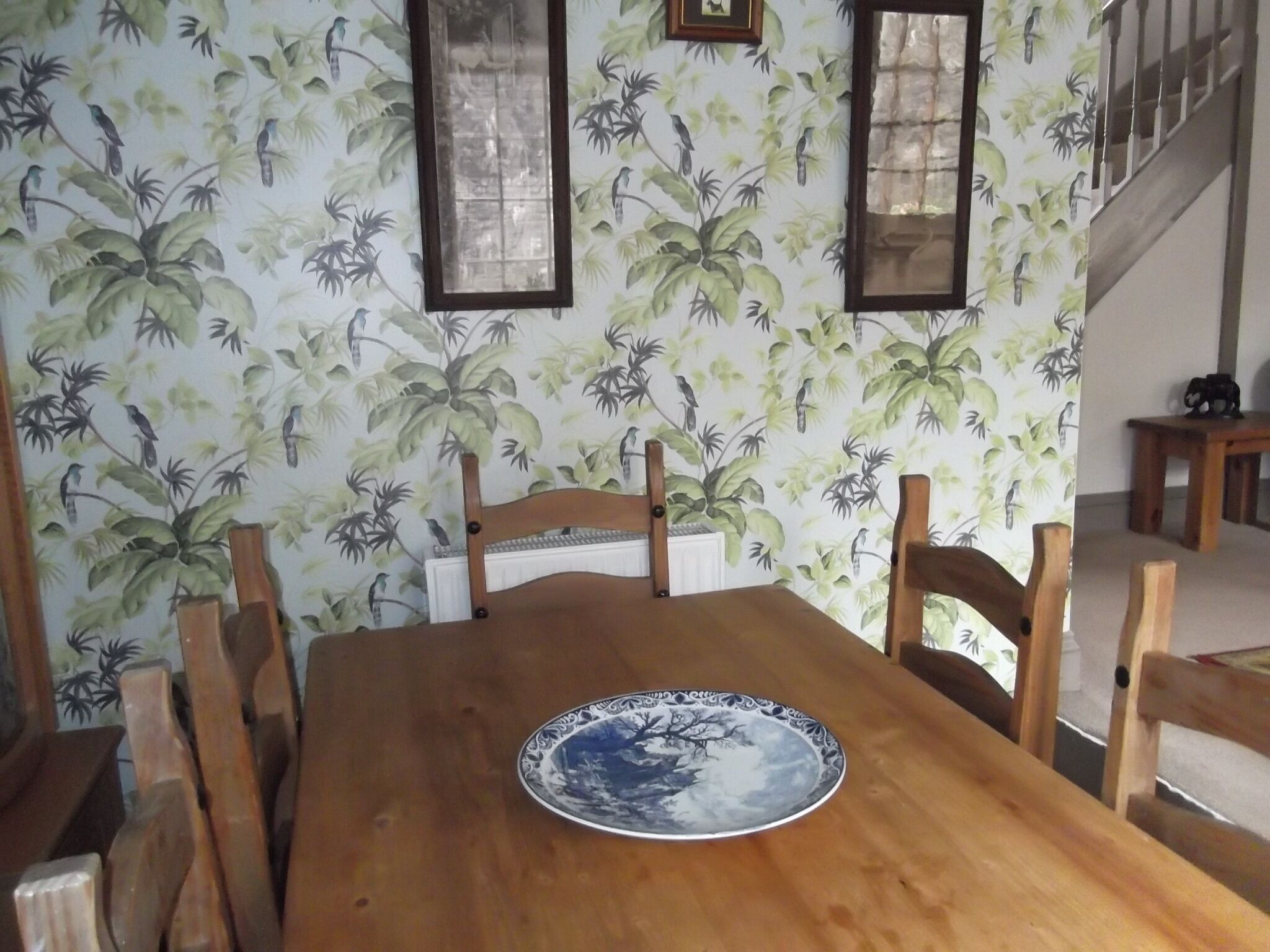 Een eetgedeelte met een houten tafel, stoelen en een decoratief bord.