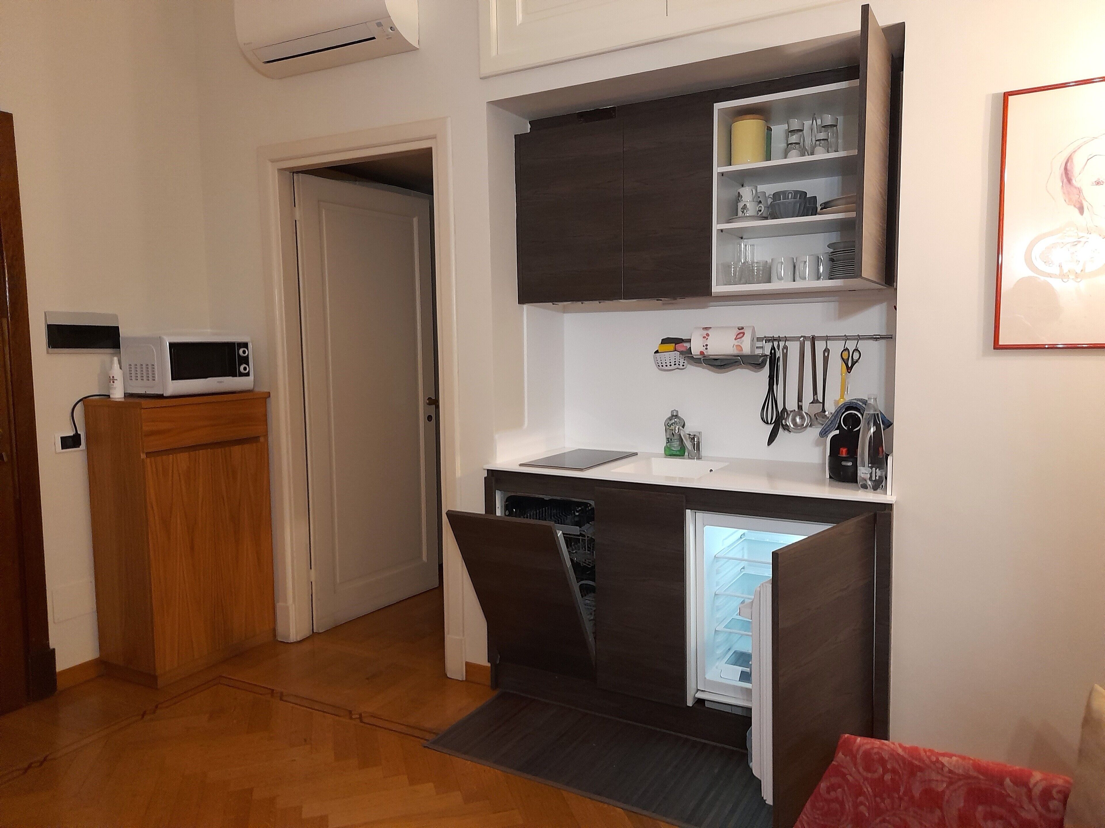 Eine kleine Küche mit Mikrowelle, Spüle und Kühlschrank.