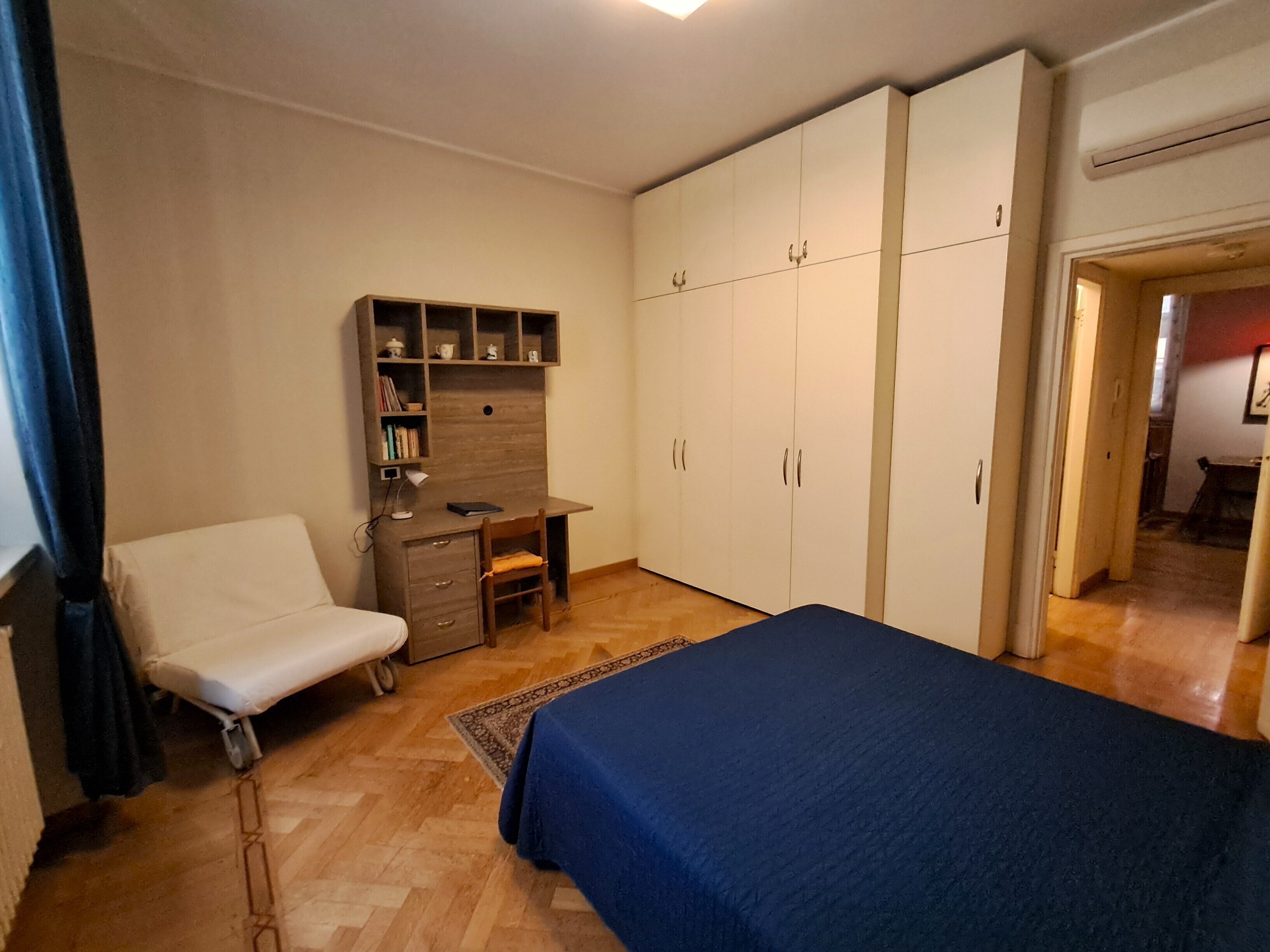A bedroom with a bed, a desk, a chair, and a wardrobe.