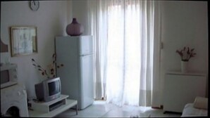 A room with a television on a stand, a white cabinet, a vase with flowers, and a window with sheer curtains. - Diamond holiday 2019 La Casa Di Fra  (Diamante)