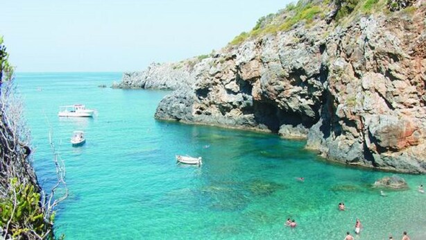 A coastal scene with rocky cliffs, clear turquoise water, and several boats. - Diamond holiday 2019 La Casa Di Fra  (Diamante)