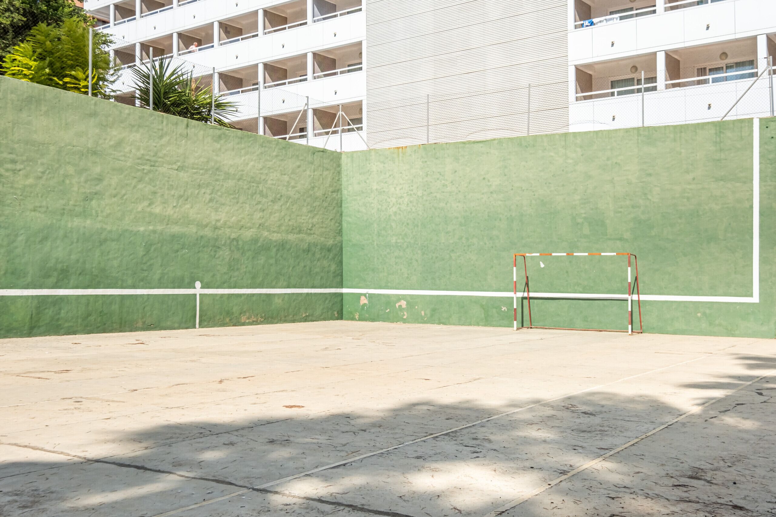 A tennis court with a green wall and a white net.
