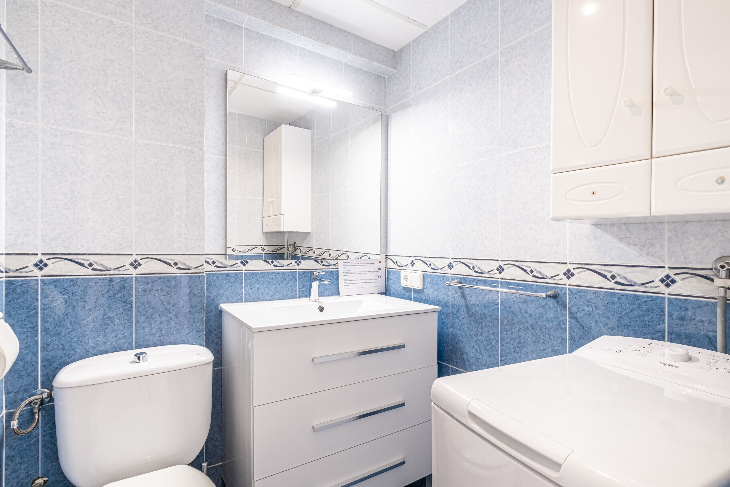 Een badkamer met toilet, wastafel en spiegel.