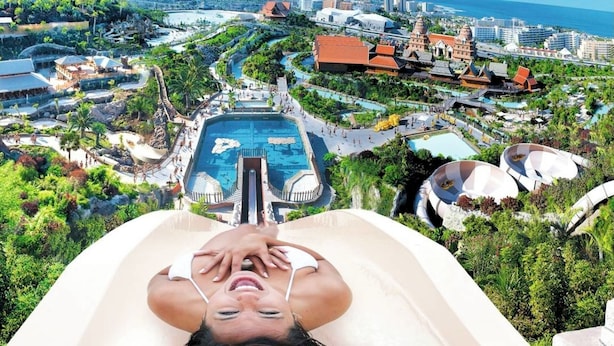 A resort with multiple pools, a large central pool, and a variety of buildings including a temple-like structure.