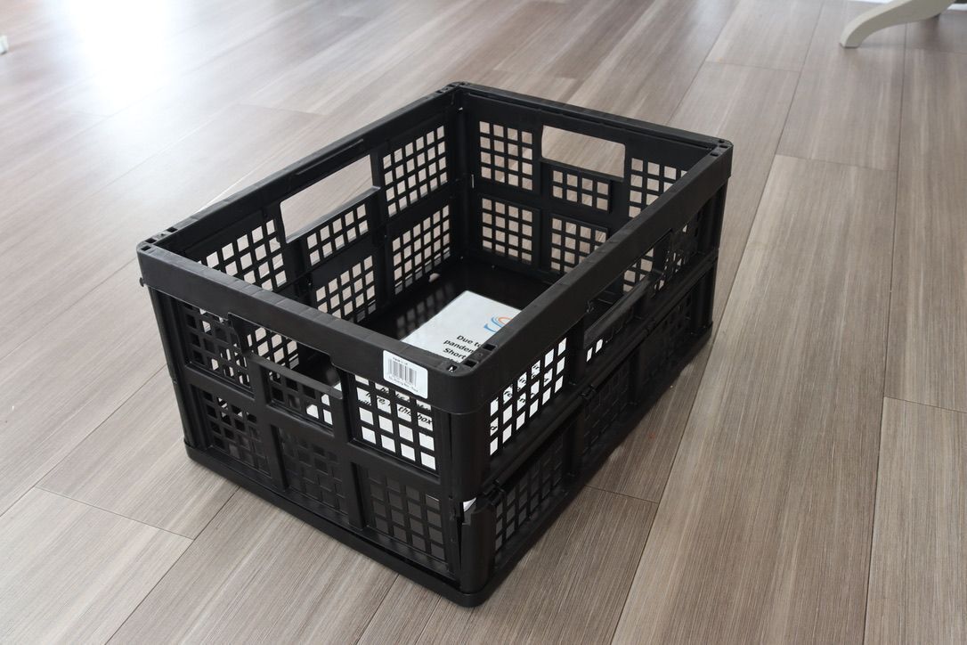 Eine schwarze Plastikkiste mit einem Etikett auf Holzgestellt.