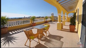 A terrace with a yellow railing, potted plants, wicker chairs, and a table. - Luxury villa with private swimming pool near Carvoeiro (Carvoeiro)