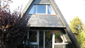 A triangular house with a large window and sliding glass doors. - Holiday house with fireplace, near the beach, dogs welcome (Ostseebad Damp)