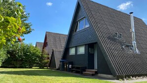 A modern house with a sloped roof, a visible chimney, and a well-maintained lawn. - Holiday house with fireplace, near the beach, dogs welcome (Ostseebad Damp)