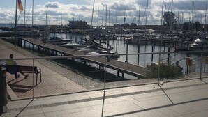 A marina with boats docked, a pedestrian walkway, and a flagpole with a flag. - Holiday house with fireplace, near the beach, dogs welcome (Ostseebad Damp)