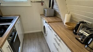 A compact kitchen with a washing machine, a microwave, and a toaster. - Holiday house with fireplace, near the beach, dogs welcome (Ostseebad Damp)