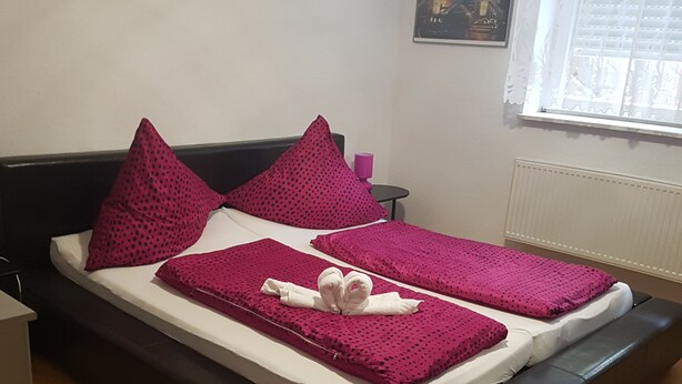 A bed with a black frame, white bedding, and pink polka dot pillows.