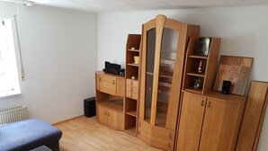 A room with a glass-top table, wooden cabinets, and a radiator.