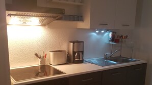 A compact kitchen with a dishwasher, a coffee maker, and a sink.