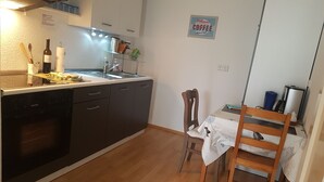 A compact kitchen with a dishwasher, a sink, and a dining area with a chair and table.