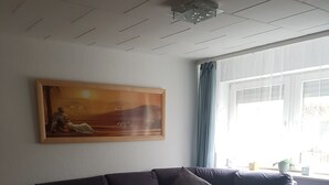 A living room with a dark purple sofa, a glass coffee table, and a painting on the wall.