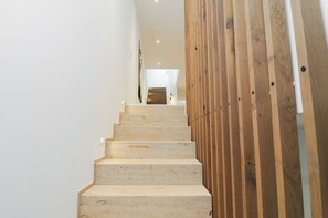 A staircase with a wooden panel on the right side, leading to a room with a white ceiling and a visible door at the top. - Stylish, newly built holiday home (Schliengen)
